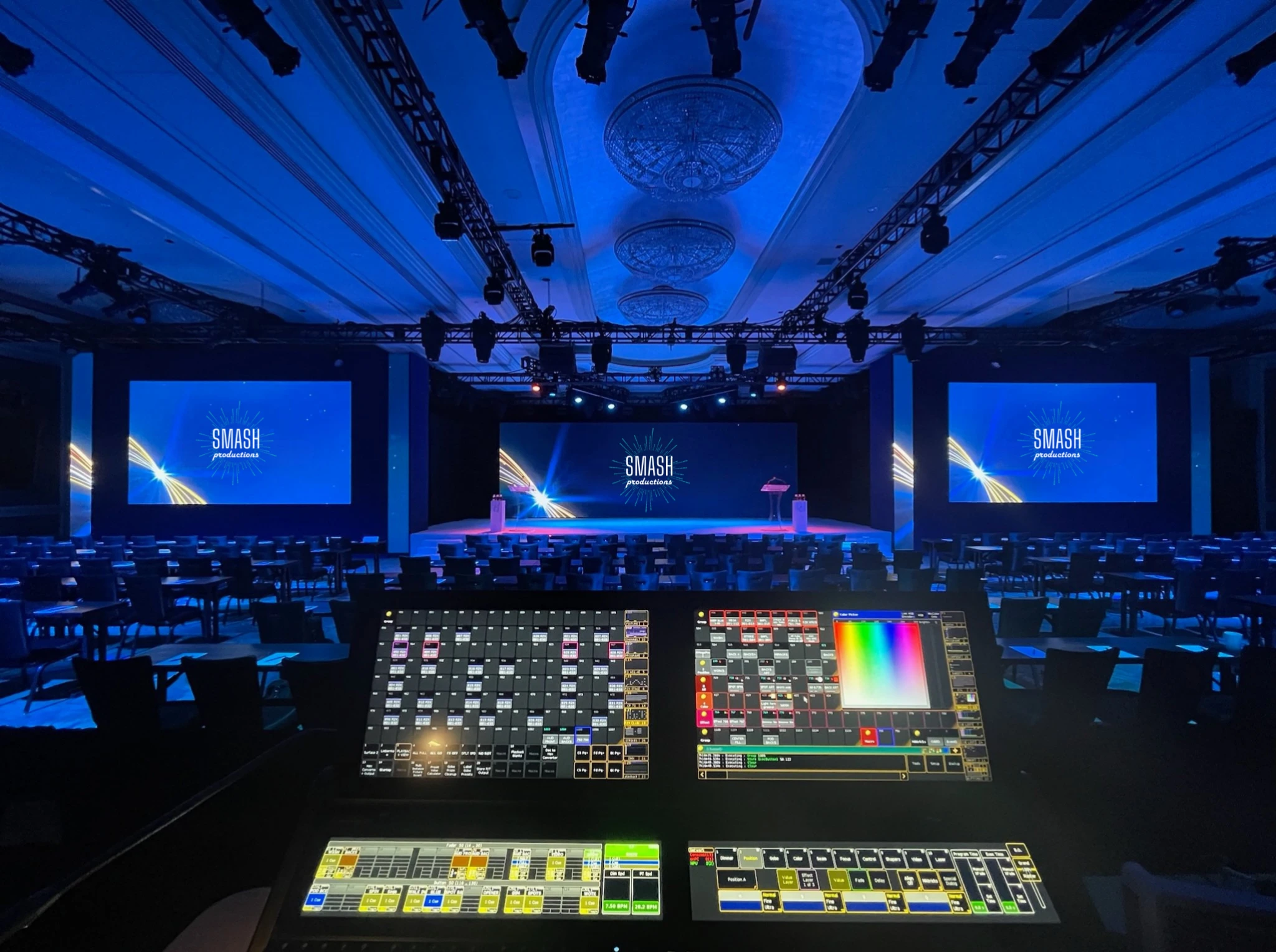 Smash Productions event stage with three branded blue screens, overhead lighting and show-control consoles in the foreground