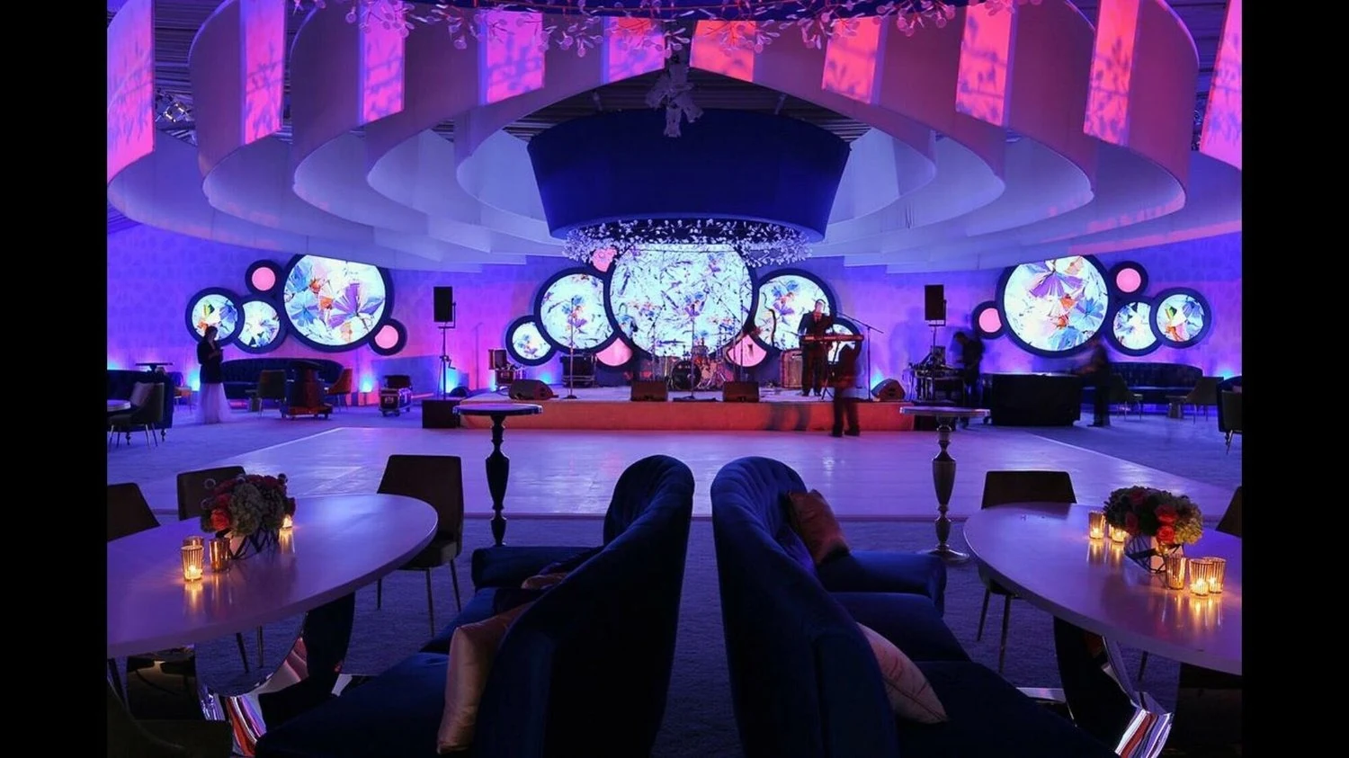 A sculptural event stage with circular screens, scenic elements and purple lighting