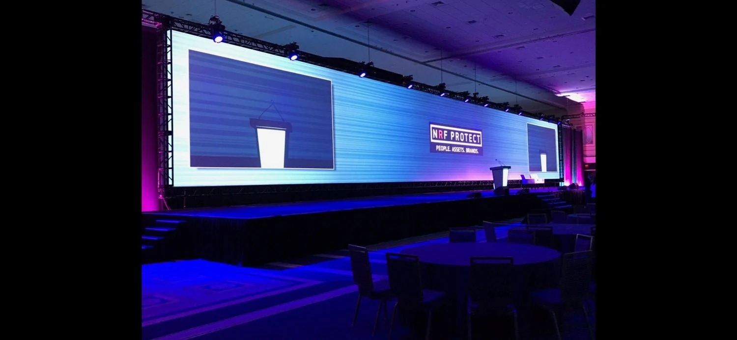 Wide event stage screen displaying branded presentation content